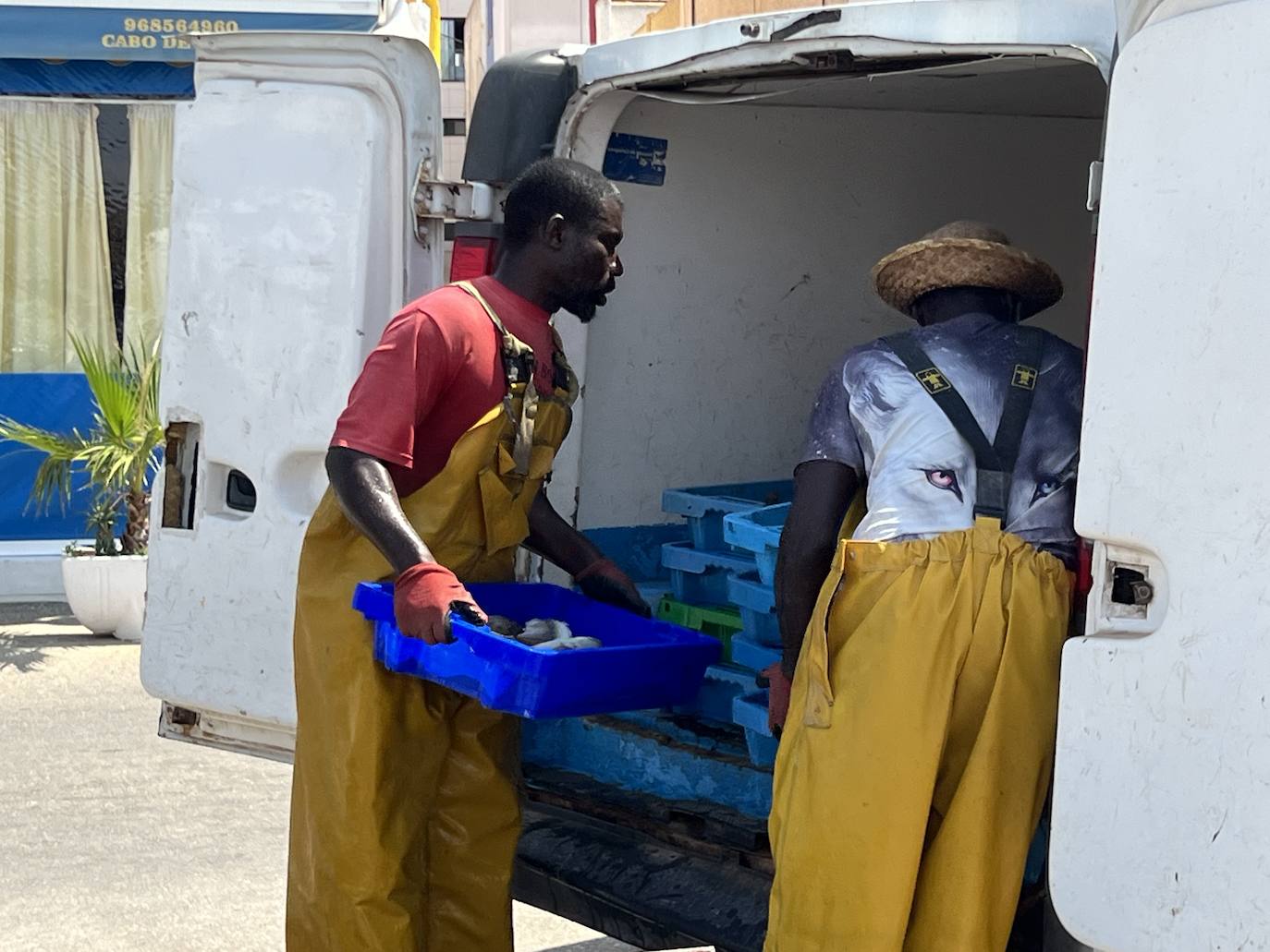 Dos pescadores de origen senegalés guardan en cámaras frigoríficas la captura del día en el puerto de Cabo de Palos.