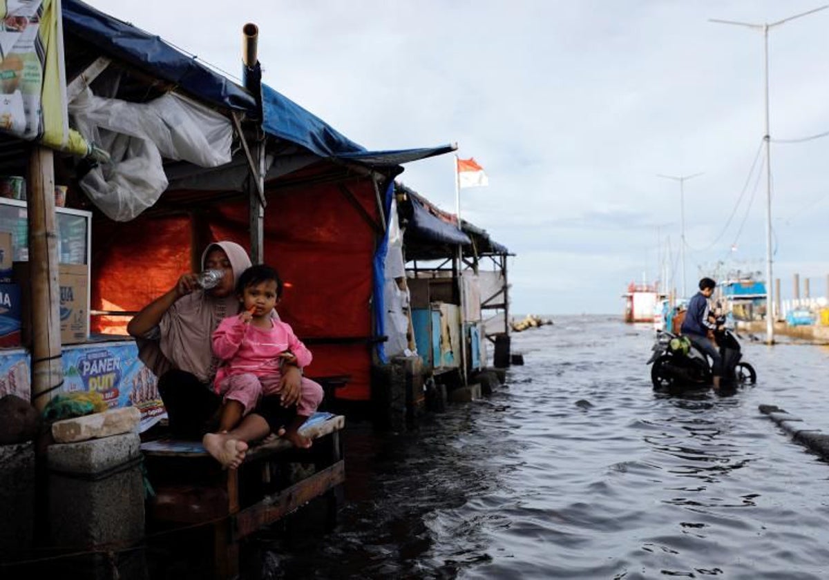 Una vendedora espera con su hija la llegada de clientes en el puerto de Muara Angke de Yakarta, inundado por las mareas
