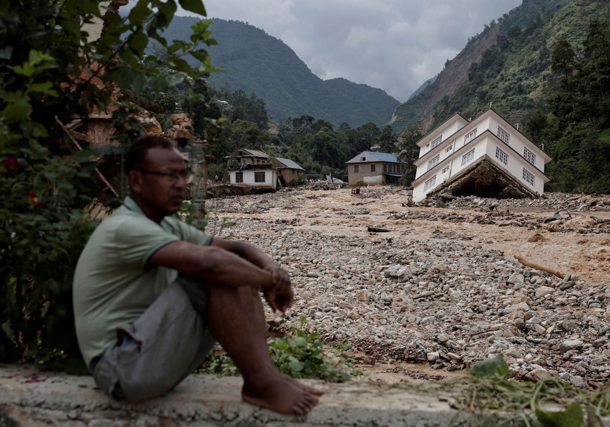 Un hombre sentado frente a una casa dañada por la inundación mortal tras las fuertes lluvias a lo largo de la orilla del río Roshi en Panauti en Kavre, Nepal