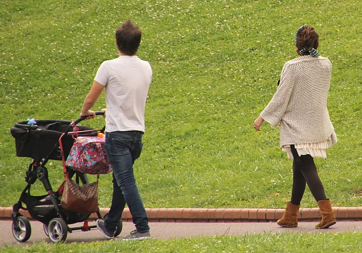 Un hombre pasea a su bebé en el parque de El Retiro de Madrid junto a su pareja