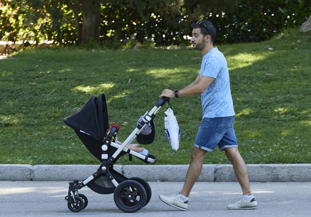 Un hombre pasea a su bebé en el parque de El Retiro de Madrid