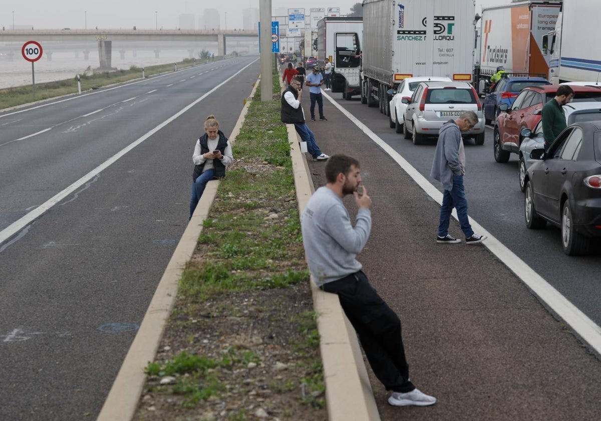 Varios conductores aguardan junto a sus vehículos en la V-30 junto al nuevo cauce del Turia durante la mañana de este miércoles