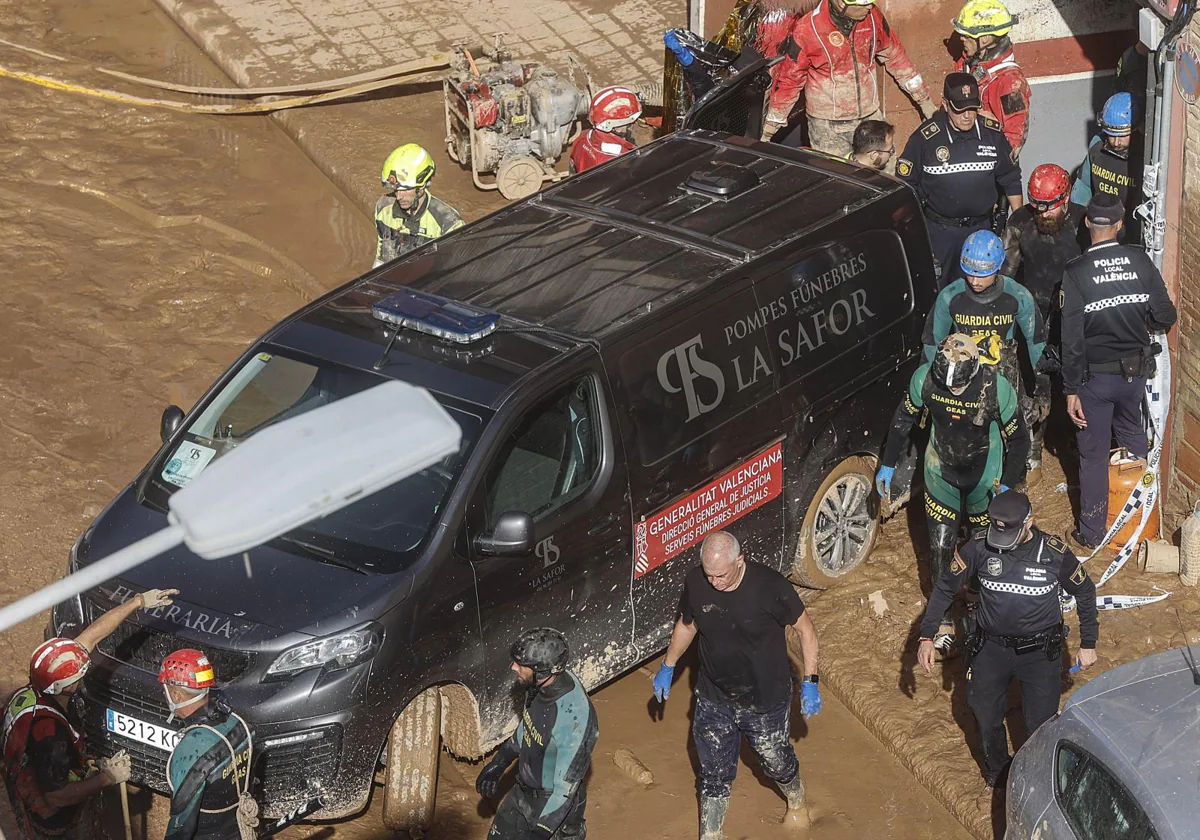 Un furgón de la funeraria sale de un garaje con cadáveres localizados tras el paso de la DANA, en el barrio de la Torre