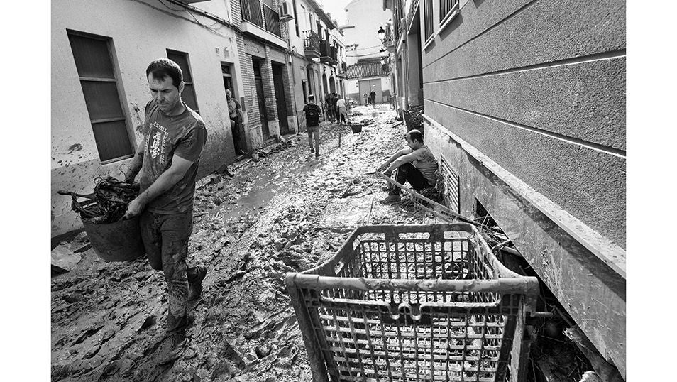 Un hombre remueve como puede los escombros de una de las calles de la localidad de Paiporta tras haber sido arrasada por la riada provocada por la DANA