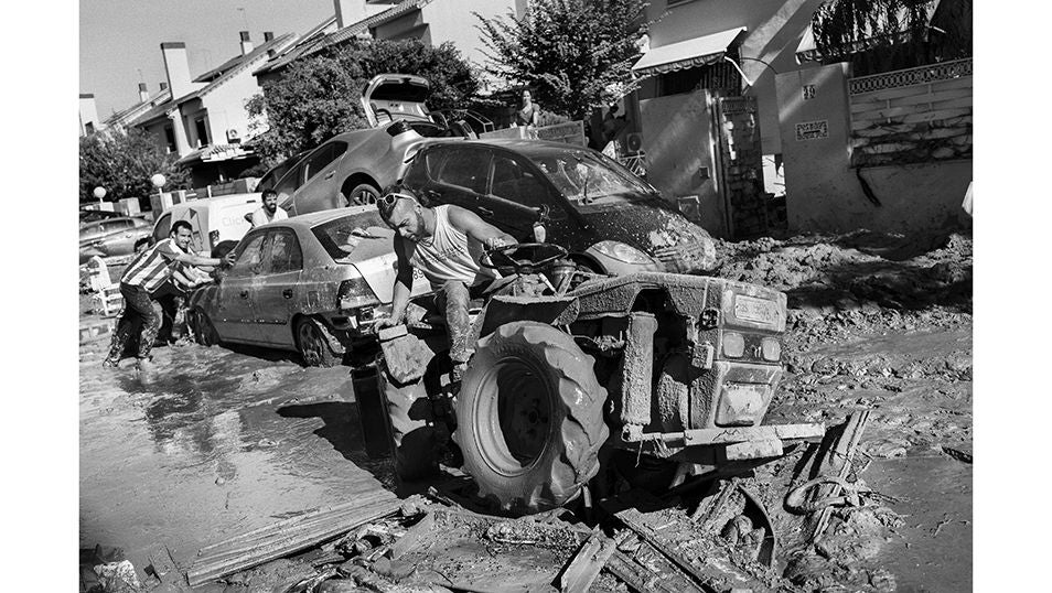 Un vecino de Pioporta intenta desenterrar un coche del lodo con la ayuda de un tractor.