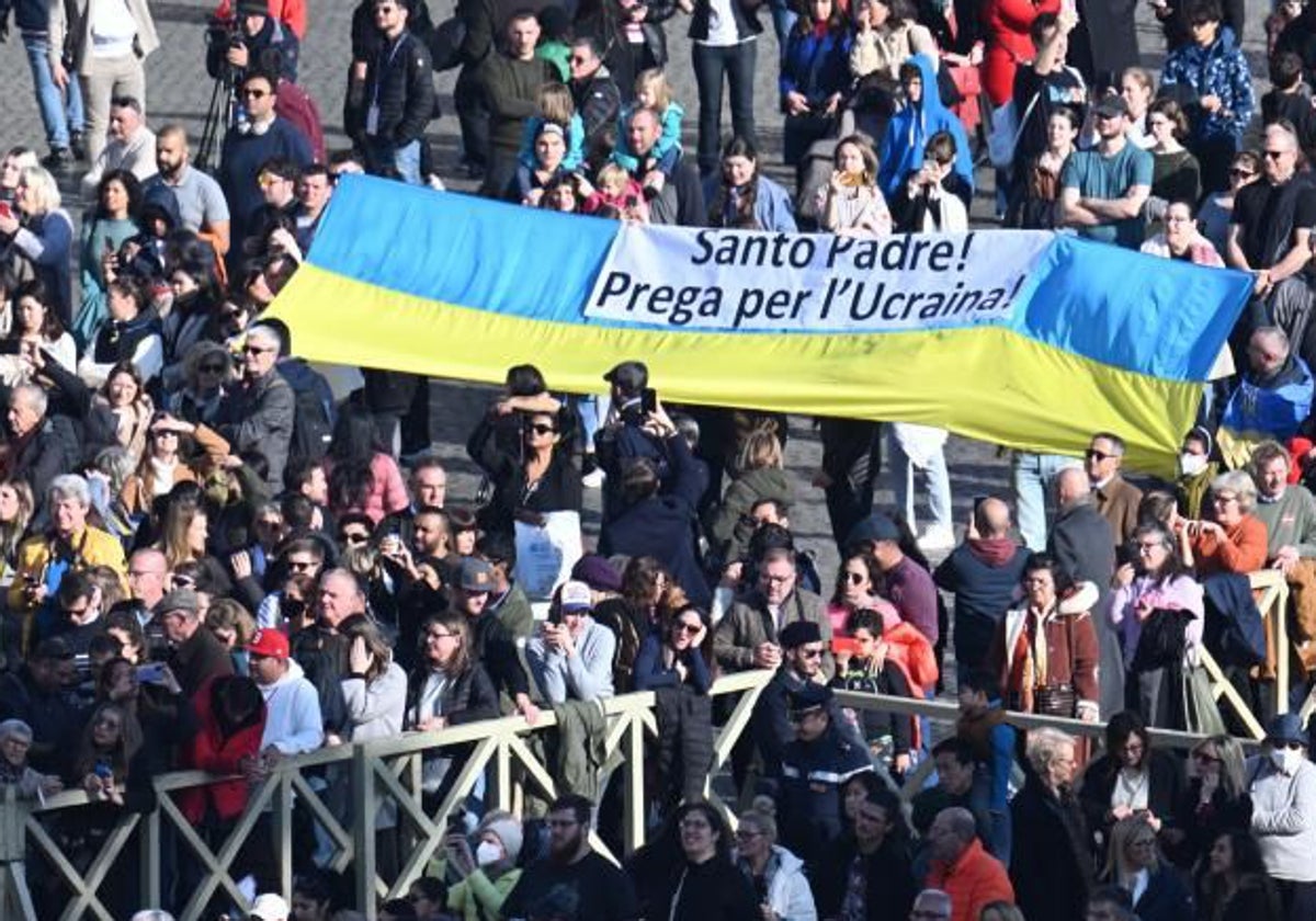 Unos peregrinos muestran la bandera de Ucrania con un mensaje al Papa en la plaza de San Pedro del Vaticano