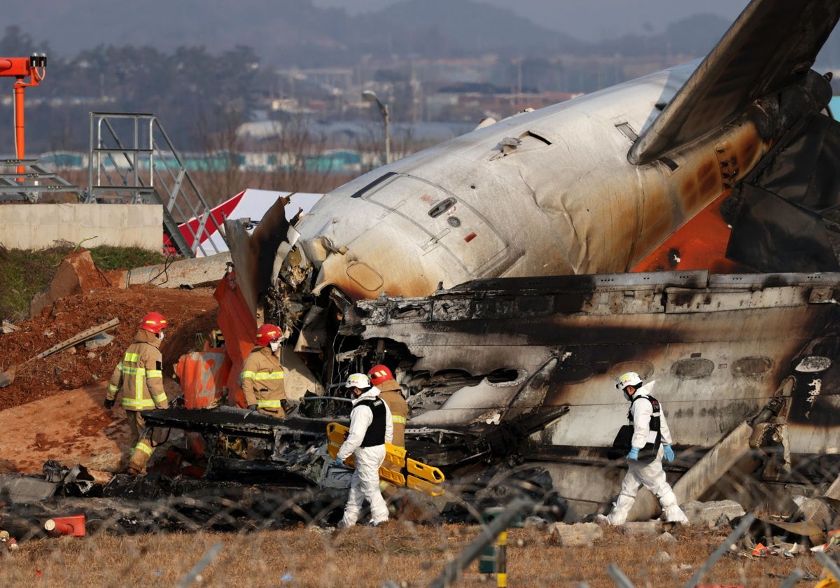 Integrantes del cuerpo del bomberos trabaja en los restos del avión de Jeju Air en el aeropuerto internacional de Muan este domingo, al suroeste de Seúl (Corea del Sur)