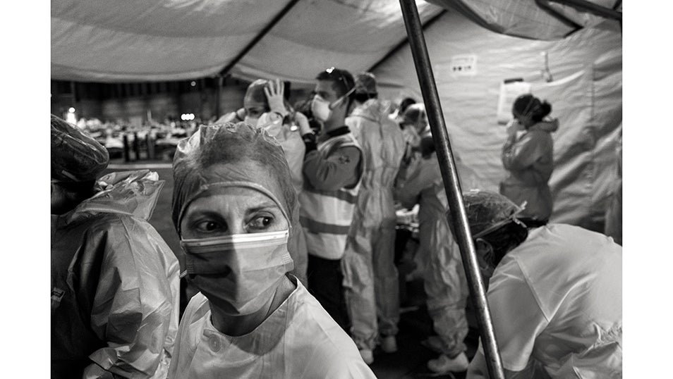 Una enfermera espera su turno para vestirse con su traje de seguridad (EPI) antes de entrar en la zona sucia del pabellón 5 del hospital de campaña de IFEMA para pacientes con COVID. Ante la presión sobre los centros médicos de la Comunidad de Madrid, el gobierno regional buscó descongestionar las hospitalizaciones instalando un hospital de campaña para tratar a pacientes con COVID-19 en uno de los mayores recintos vacíos de la capital de España. En 48 horas, la Feria de IFEMA en Madrid se convirtió en el mayor hospital de campaña temporal para COVID en España. Se estima que la pandemia ha causado más de 70.000 muertes en España, de las cuales más de 50.000 han sido confirmadas mediante pruebas PCR. Según un estudio de seroprevalencia, hasta junio, el 5% de la población española había sido infectada por el virus.