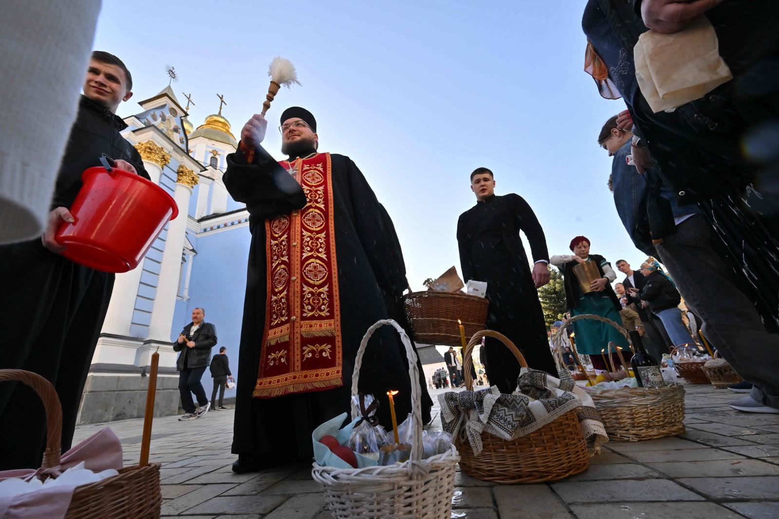 Un sacerdote ortodoxo bendice a los creyentes y sus cestas cargadas de pasteles y huevos en la Catedral de las Cúpulas Doradas de San Miguel en Kiev.