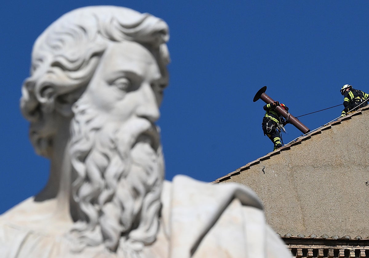 Un equipo de bomberos prepara la chimenea desde donde saldrá la fumata que anuncie al nuevo Papa
