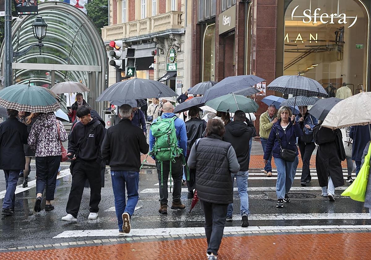 Viandantes aguantan la lluvia este viernes el Bilbao