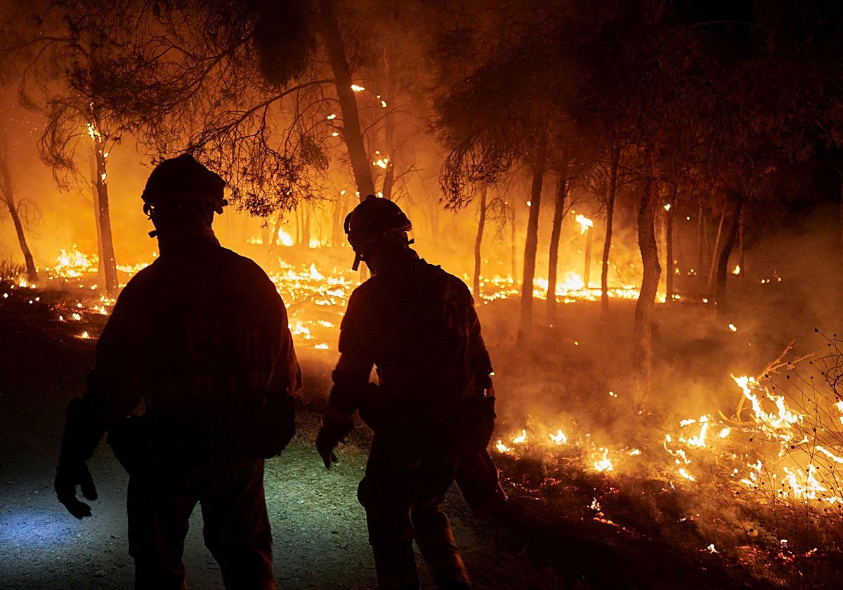 Dos bomberos trabajan para impedir que el incendio se propague, a 10 de agosto de 2025, en Carcastillo, Navarra