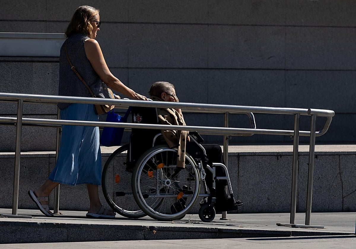 Una anciana dependiente es acompañada por una familiar en un paseo