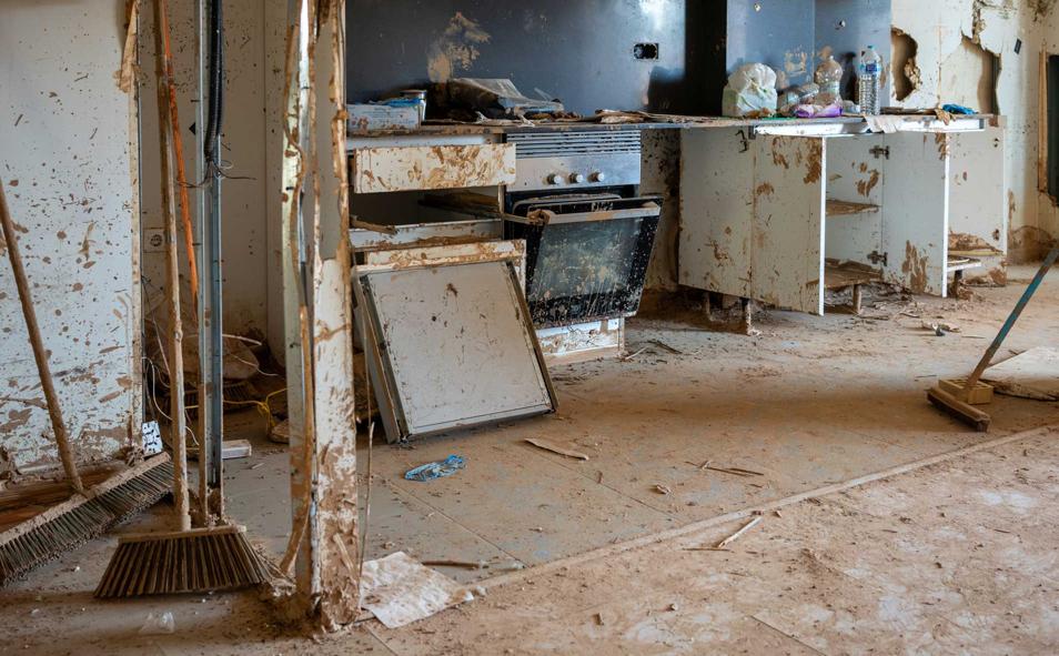 Imagen principal - Raquel tenía claro que su hija se llamaría Giulia y, con barro, lo dejó plasmado en la pared de su casa, destrozada. Un año después, el fango ya seco aún cubre los enseres.