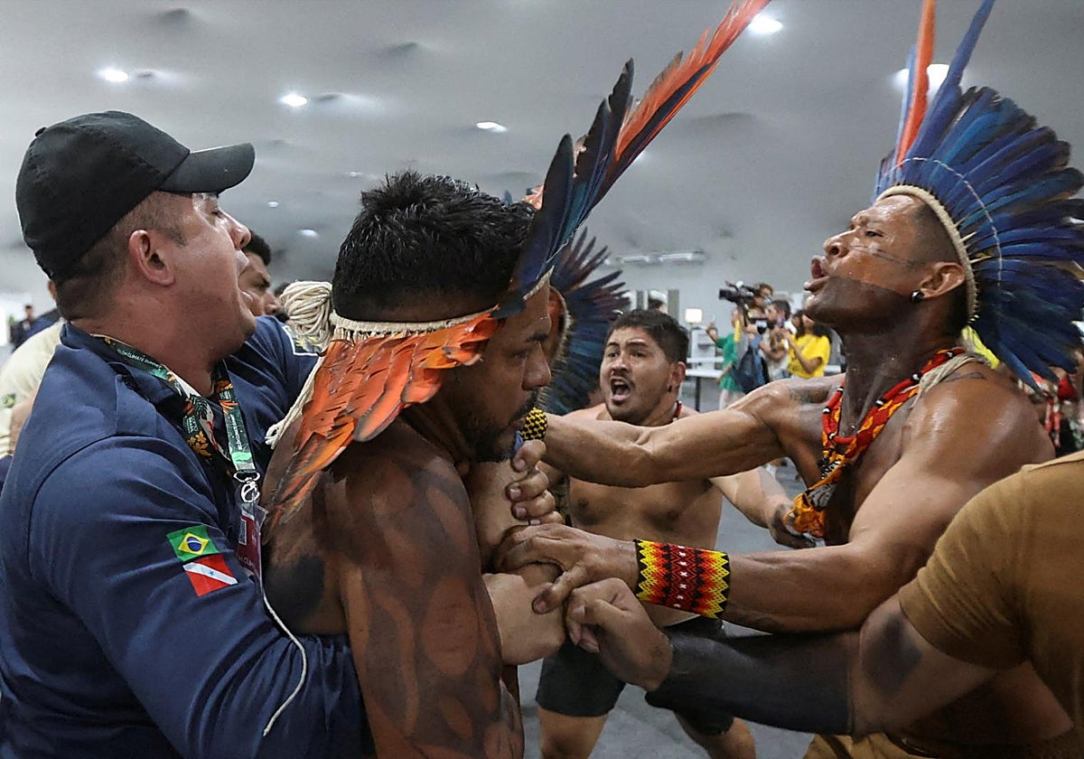 Un manifestante indígena es sujetado por un miembro del personal mientras los manifestantes irrumpen en el recinto