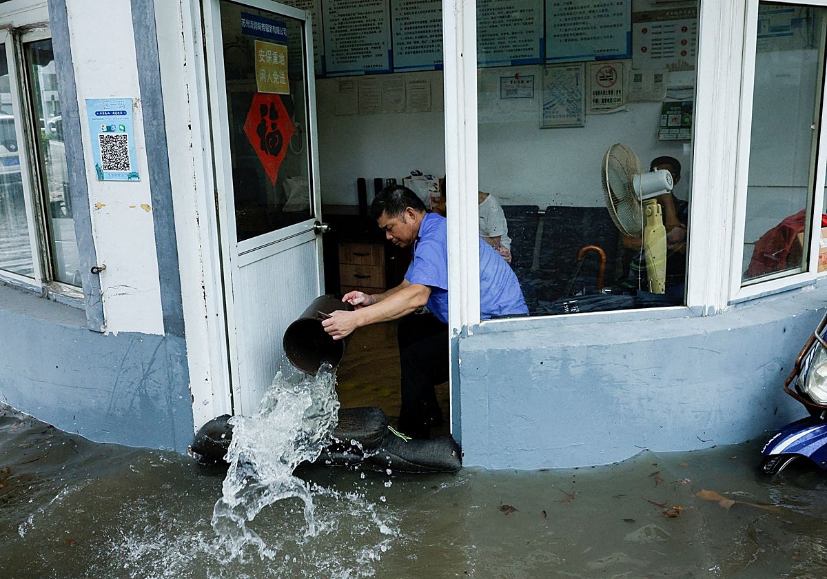 Una persona intenta sacar el agua de una habitación inundada a causa del tifón Delfín en Shanghai