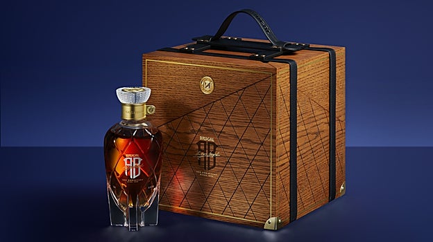 La botella está acompañada de una caja que simula un maletín de viaje