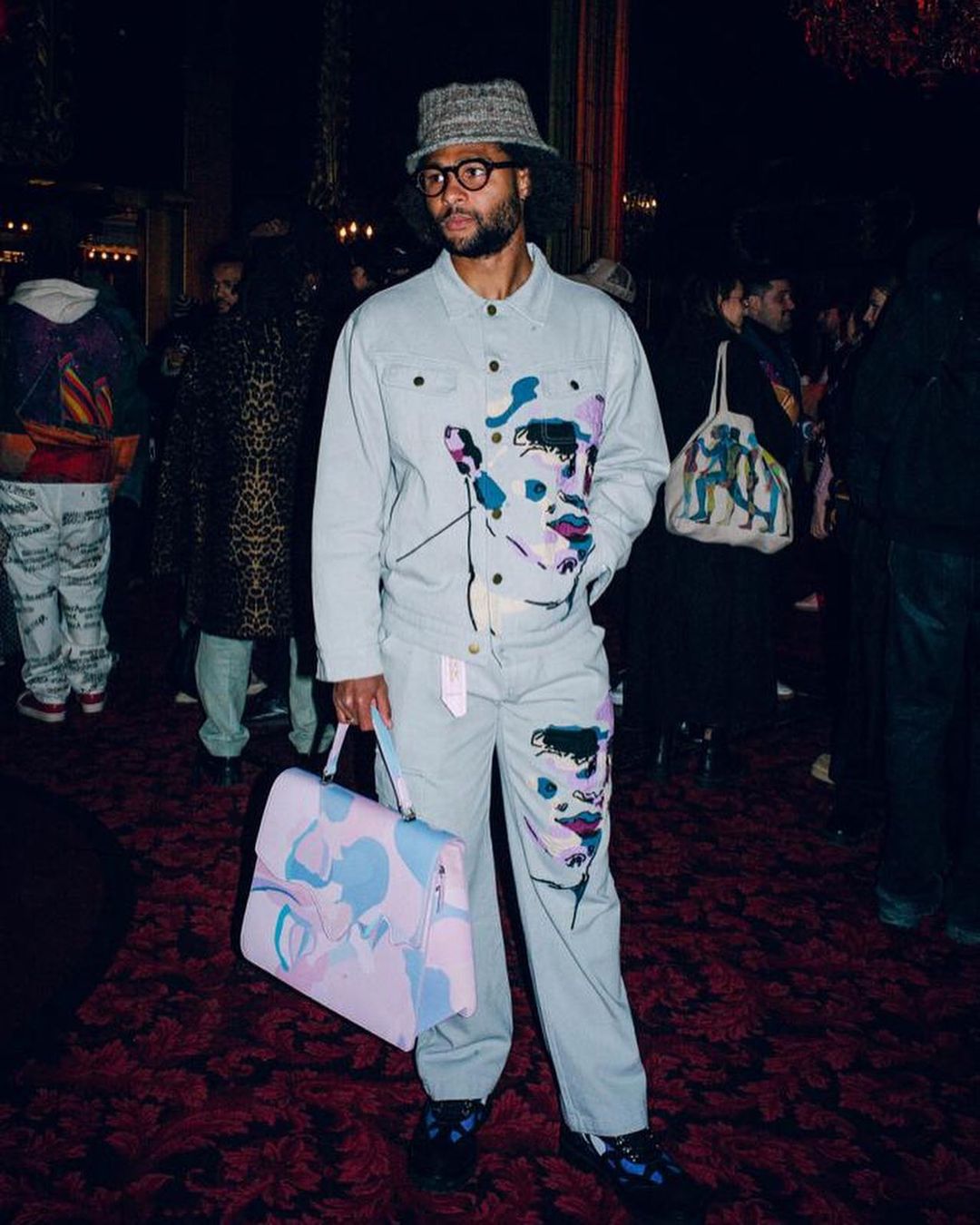 Serge Gnabry es otro futbolista que se atreve a marcar la diferencia a través de la ropa y los accesorios. La mejor prueba está en esta imagen, en la que luce un traje estampado combinado con un gorro tipo bucket y un gran bolso multicolor.