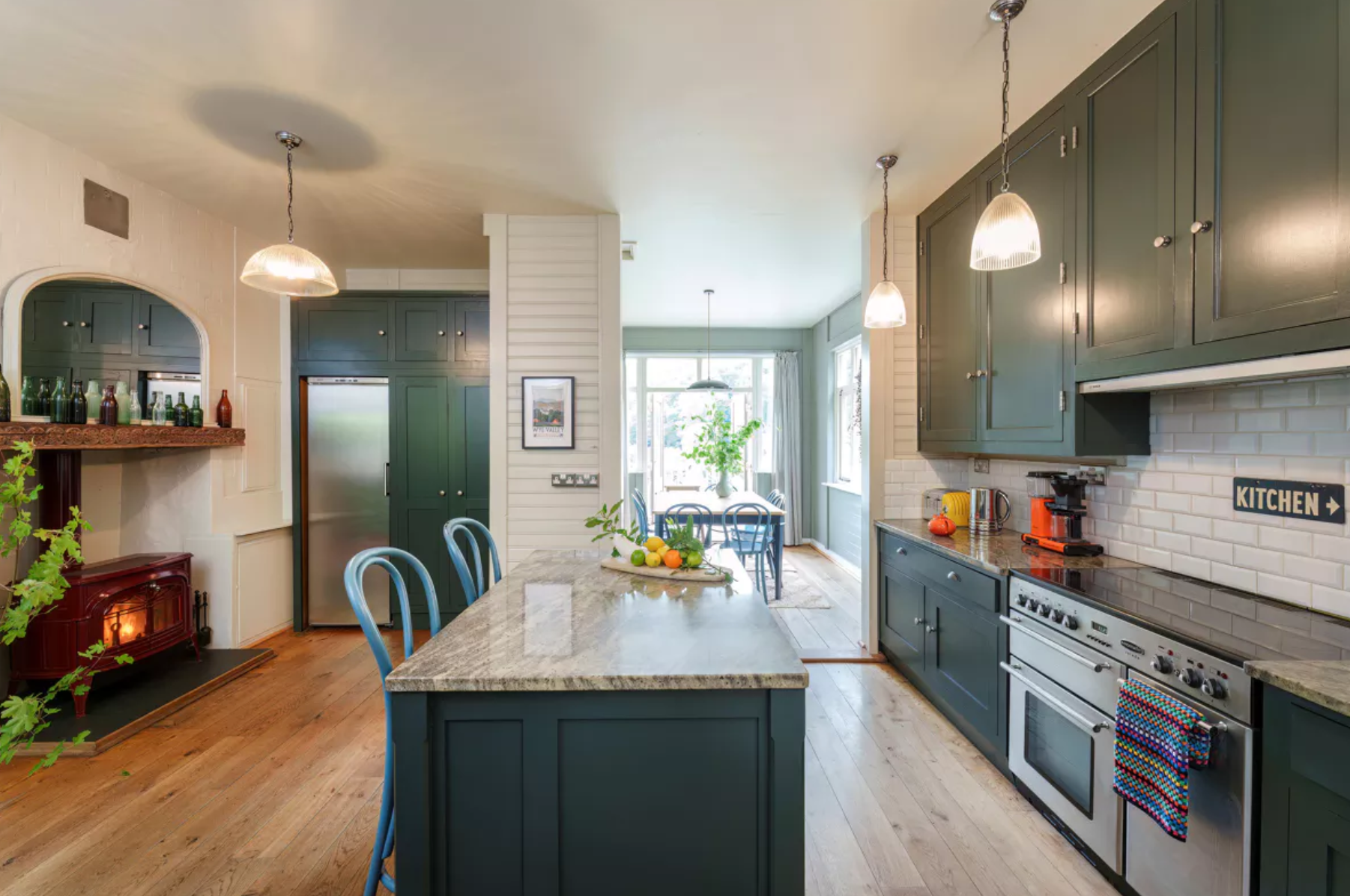 La cocina dispone de gabinetes en azul turquesa oscuro, electrodomésticos de acero inoxidable y una isla con espacio extra de almacenaje