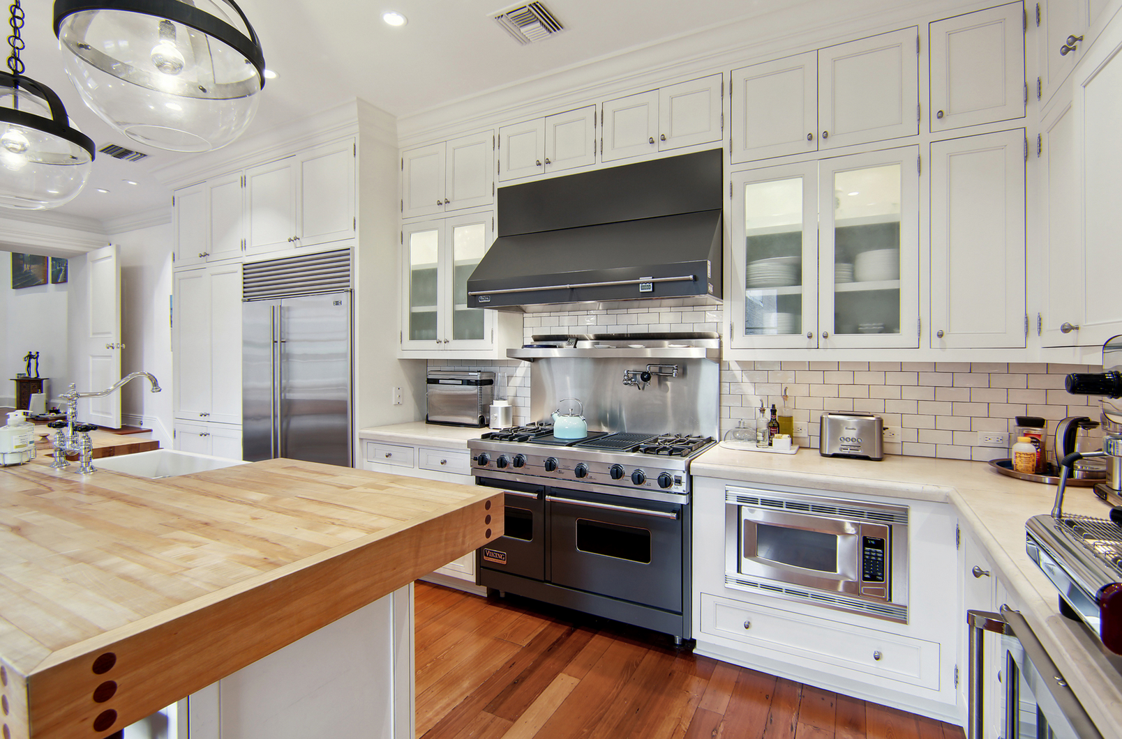 La cocina cuenta con gabinetes en color blanco, electrodomésticos de alta gama y una isla con barra de desayuno y fregadero