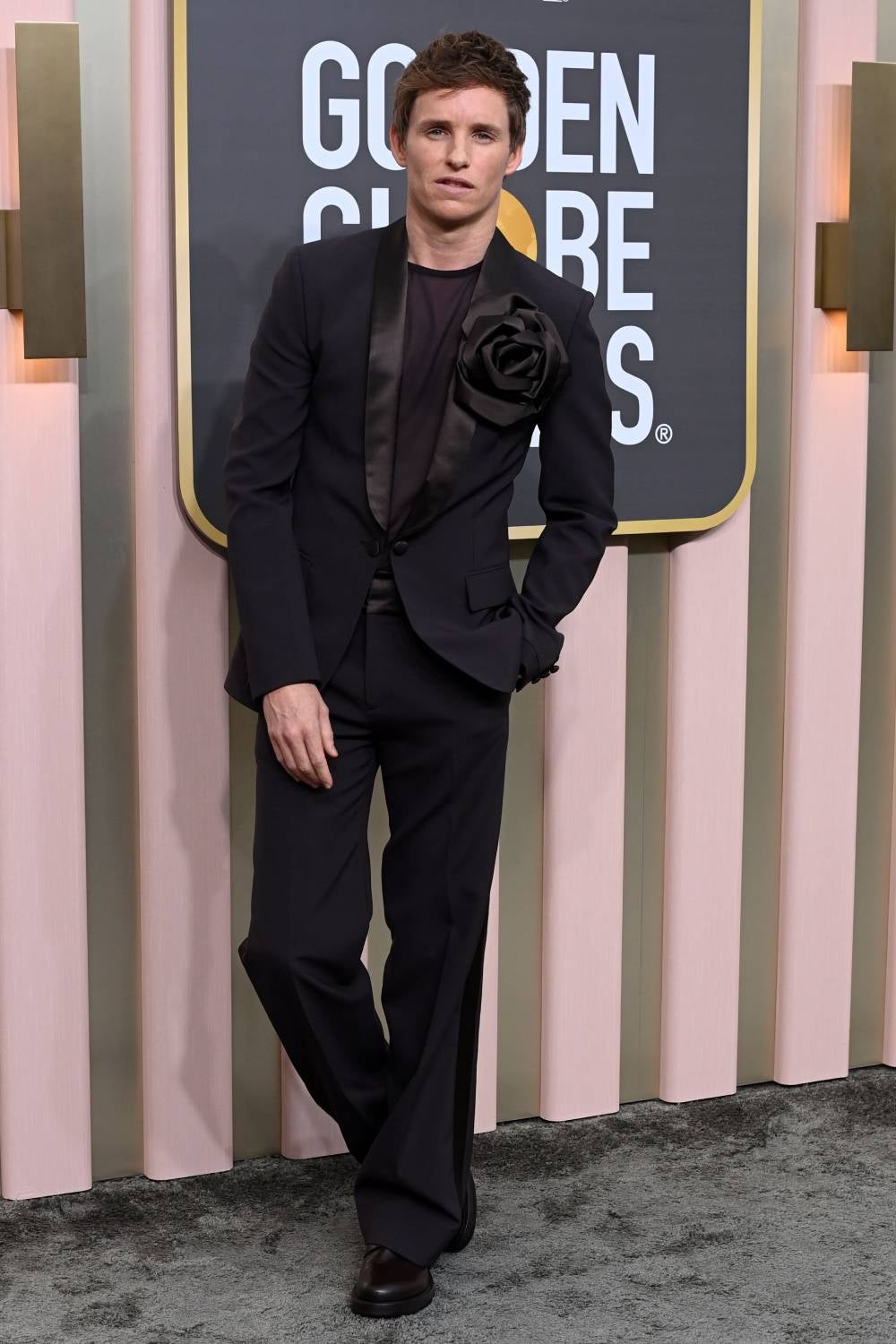 Eddie Redmayne es siempre un referente a la hora de defender piezas originales de sastrería y en la última edición de los Globos de Oro volvió a demostrarlo con un traje marrón firmsdo por Valentino con flor en la solapa.