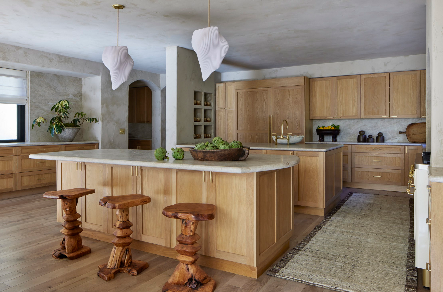 La cocina cuenta con gabinetes de madera, encimeras de mármol, electrodomésticos de alta gama y dos islas, una de ellas con barra de desayuno