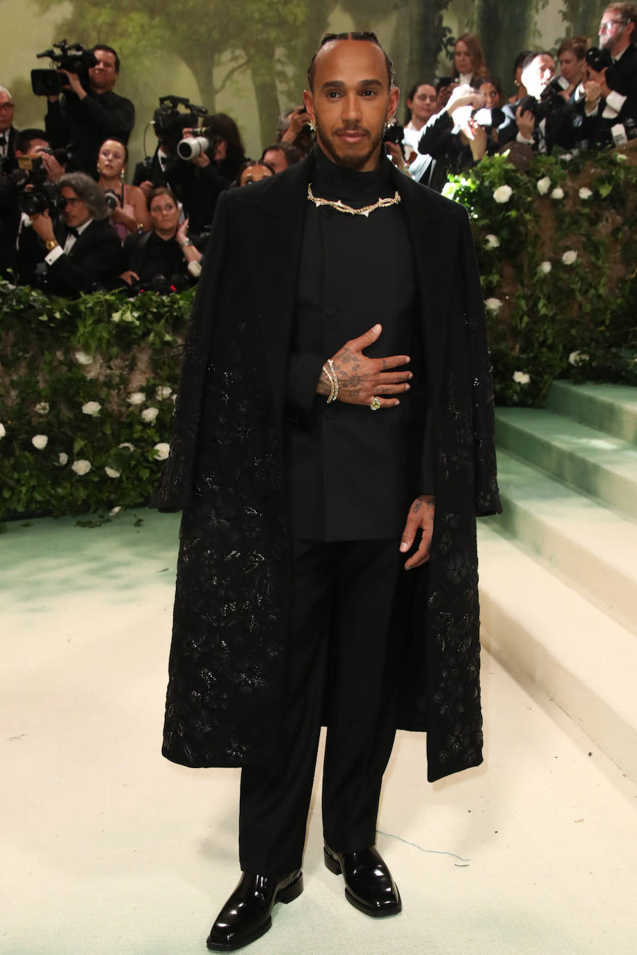 Lewis Hamilton, gran amante de la moda, no se perdió la cita y acudió con un total look black que incluía un traje con un detalle dorado en el cuello y un abrigo con bordados metalizados. 