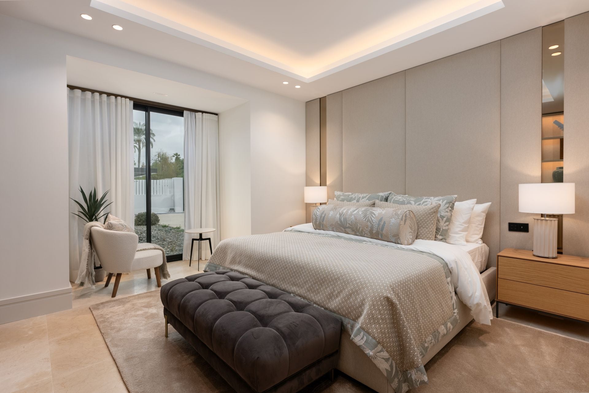 Uno de los 5 dormitorios de la vivienda, equipado con cama de gran tamaño, tonos neutros y grandes ventanales que nutren a la estancia de una magnífica luz natural. 