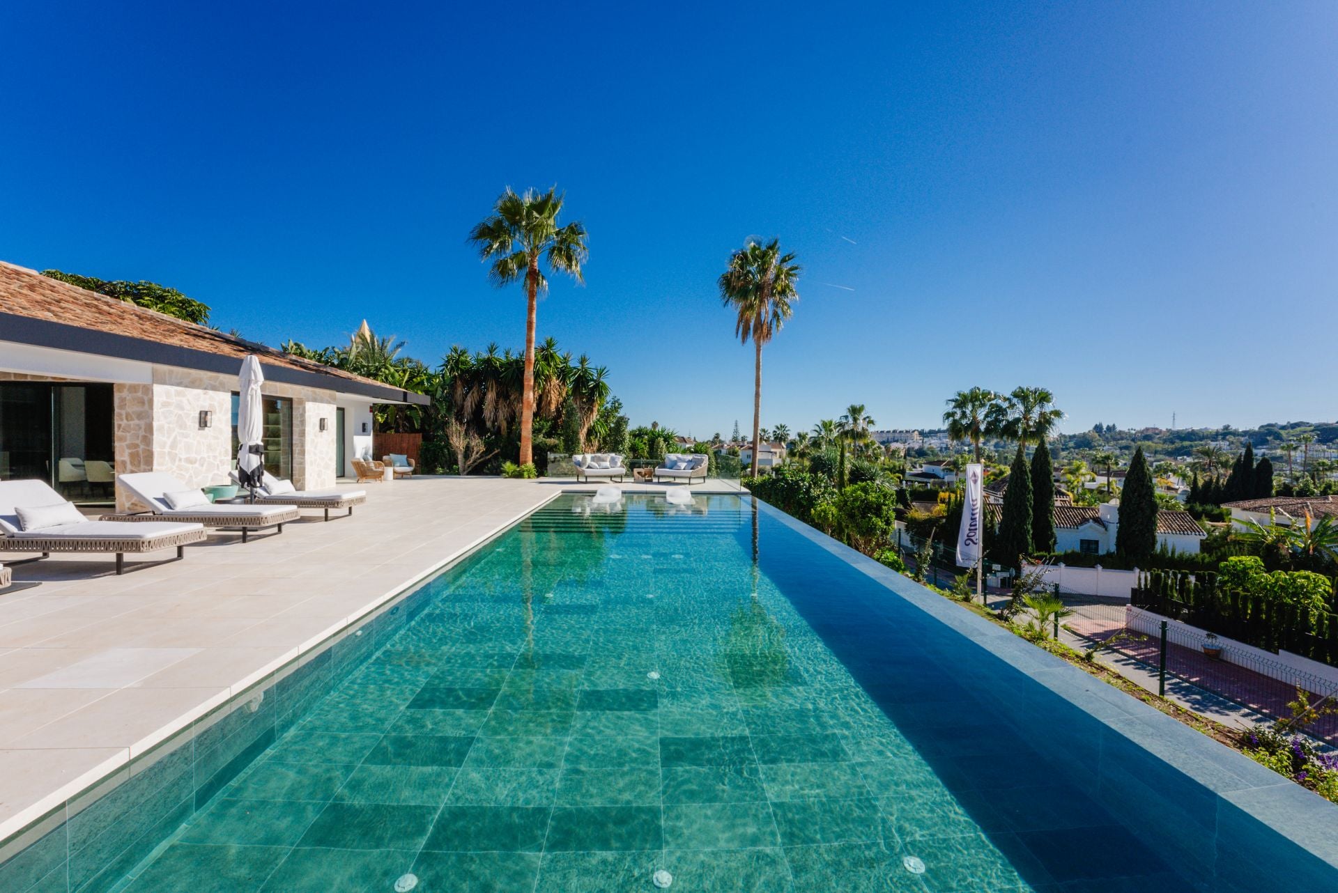 La zona exterior de la vivienda acoge una gran piscina infinita rodeada de una terraza con zona de barbacoa y bar, gimnasio exterior, solárium y comedor al aire libre.