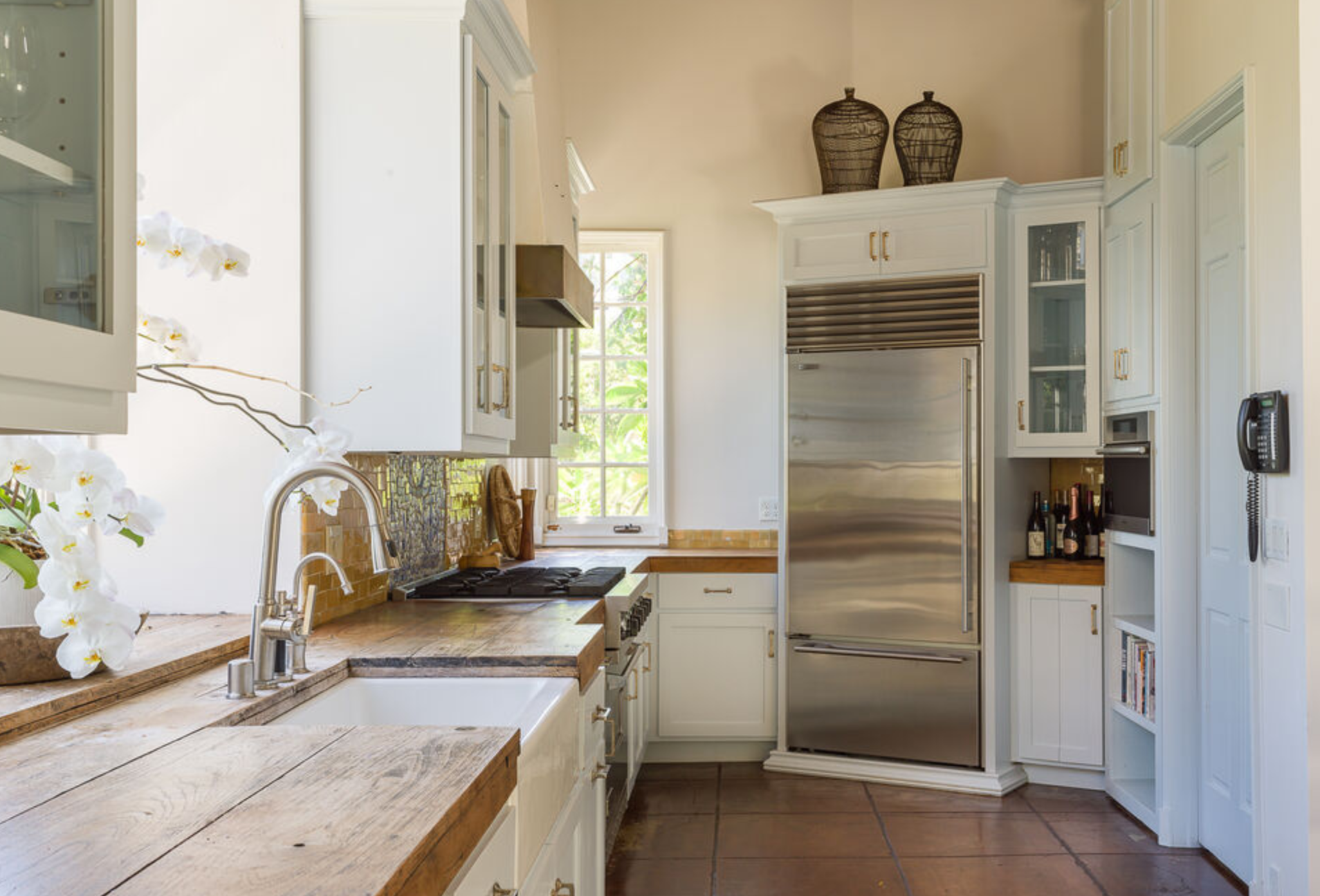 La cocina cuenta con gabinetes en color blanco, encimeras de madera y electrodomésticos de acero inoxidable