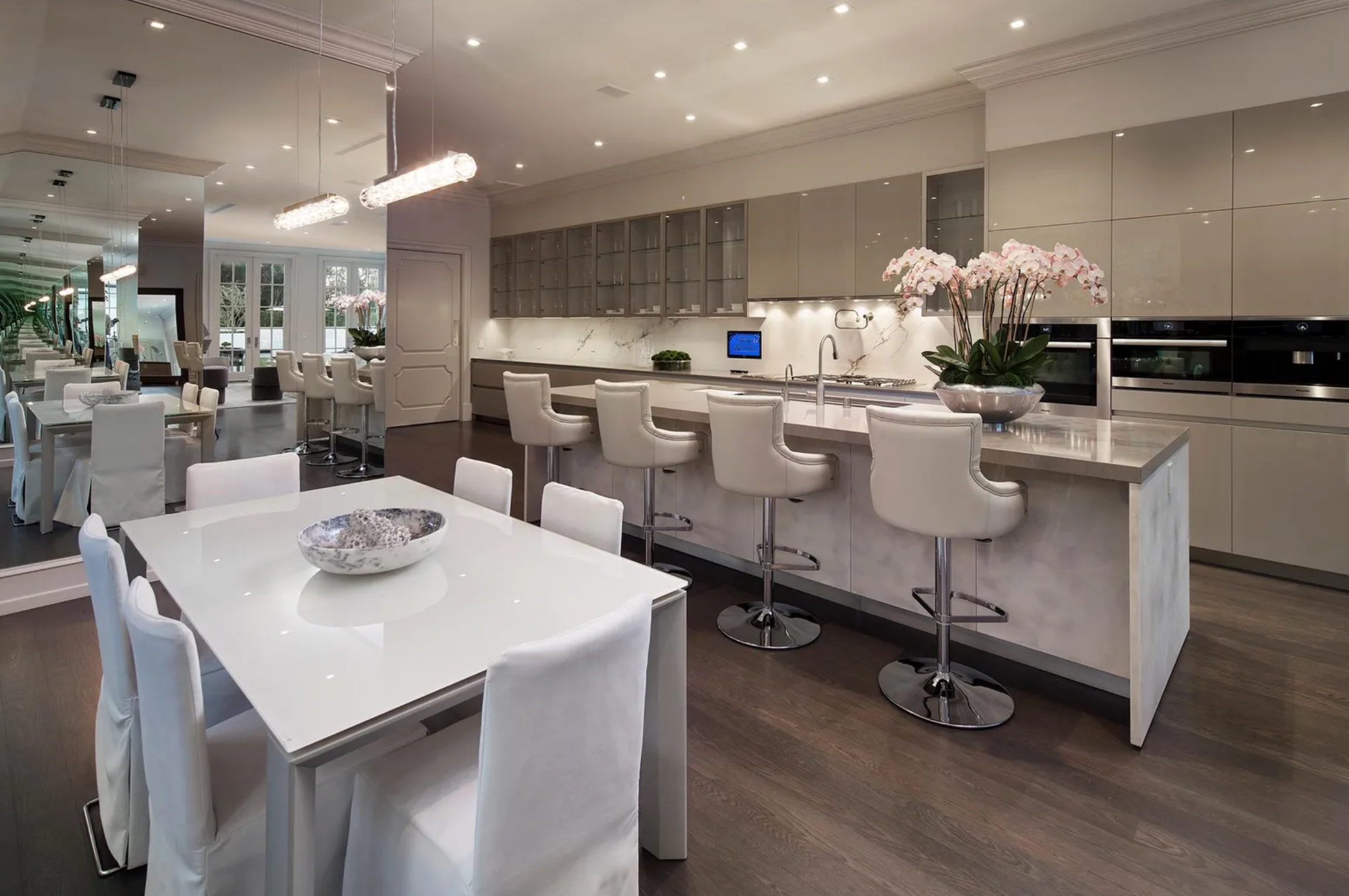 La cocina incluye electrodomésticos de acero inoxidable de alta gama, una isla central con barra de desayuno y fregadero y una mesa con capacidad para seis comensales 