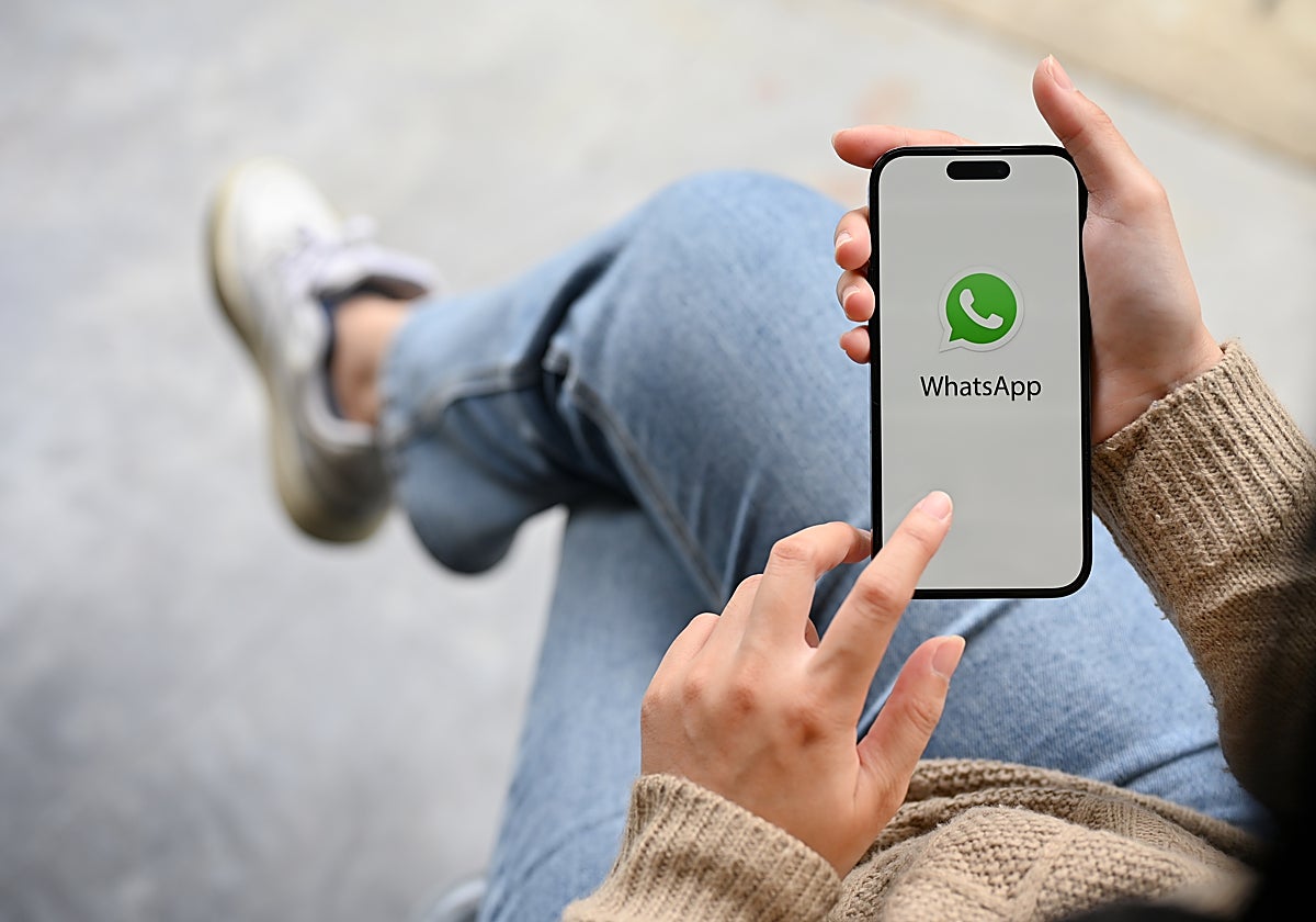 Fotografía de una mujer abriendo WhatsApp en su teléfono móvil