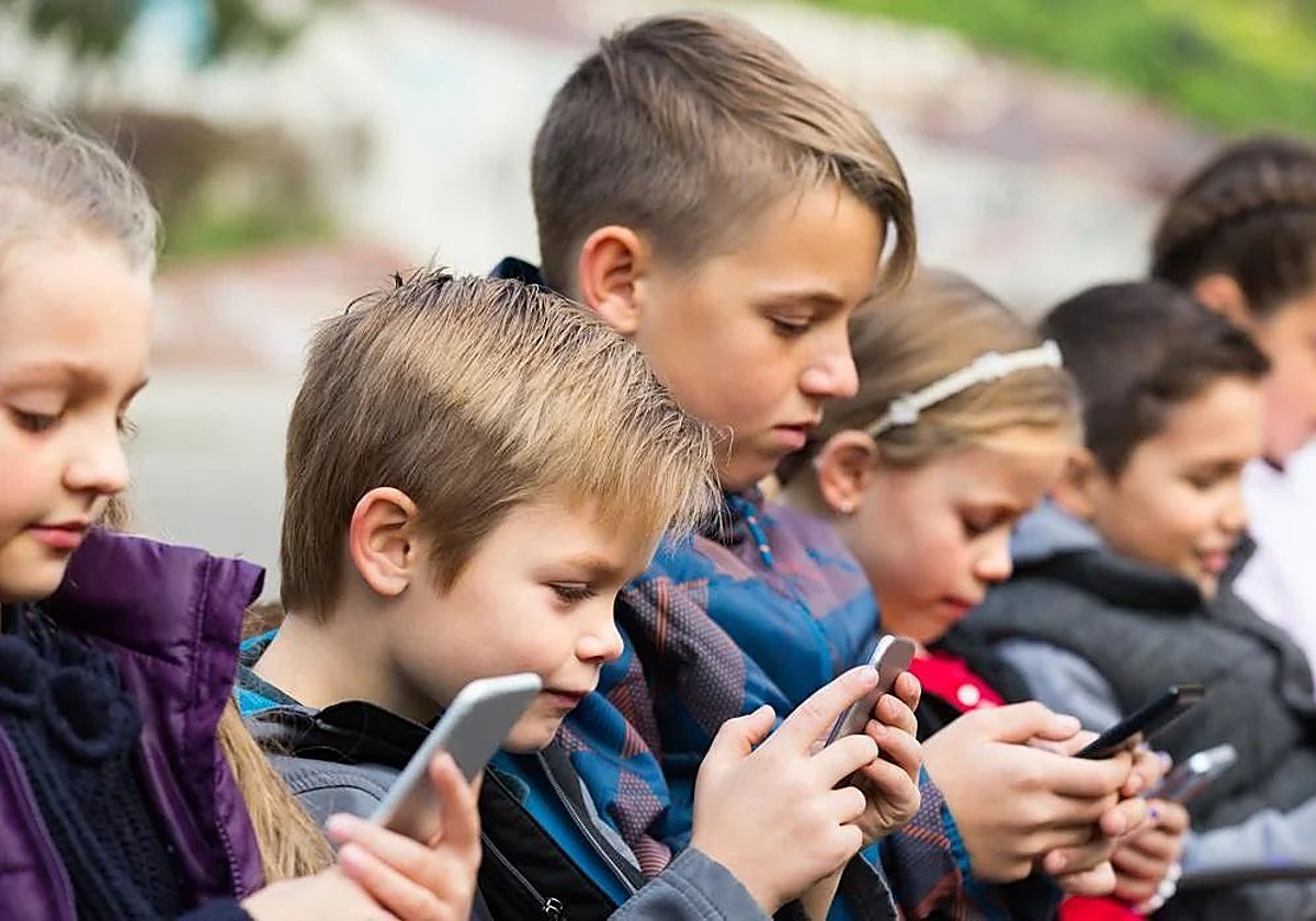 Varios niños utilizando el móvil en una imagen de archivo