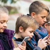 Varios niños utilizando el móvil en una imagen de archivo