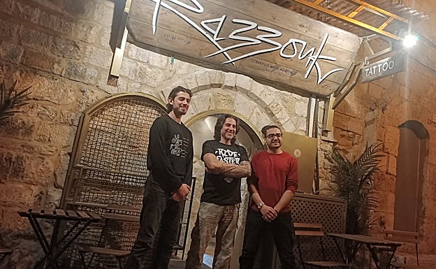 Wassim Razzouk en la puerta de su establecimiento en Jerusalén junto a sus dos hijos, la generación número 28 de tatuadores