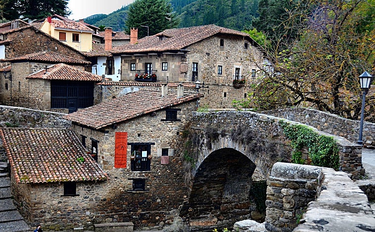 Imagen principal - Arriba, el Puente de San Cayetano, en Potes (Cantabria). Sobre estas líneas, a la derecha, Pedro Álvarez, cronista oficial de Liébana, en la Puerta del Perdón, en Santo Toribio de Liébana, a tres kilómetros del pueblo. A la izquierda, la Torre del Infantado, en Potes.