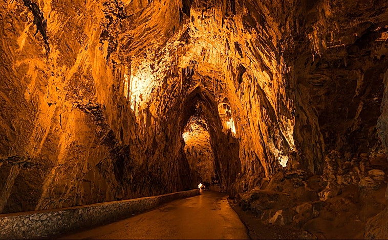 Imagen principal - lLa Cuevona es una de las contadas cavidades naturales del mundo cruzada de extremo a extremo por una carretera asfaltada -decididamente angosta en este caso-, que va a morir entre las casas de Cuevas del Agua. Sobre estas líneas, a la izquierda, una panera, antigua edificación rural sobre pilares para almacenar el cereal.