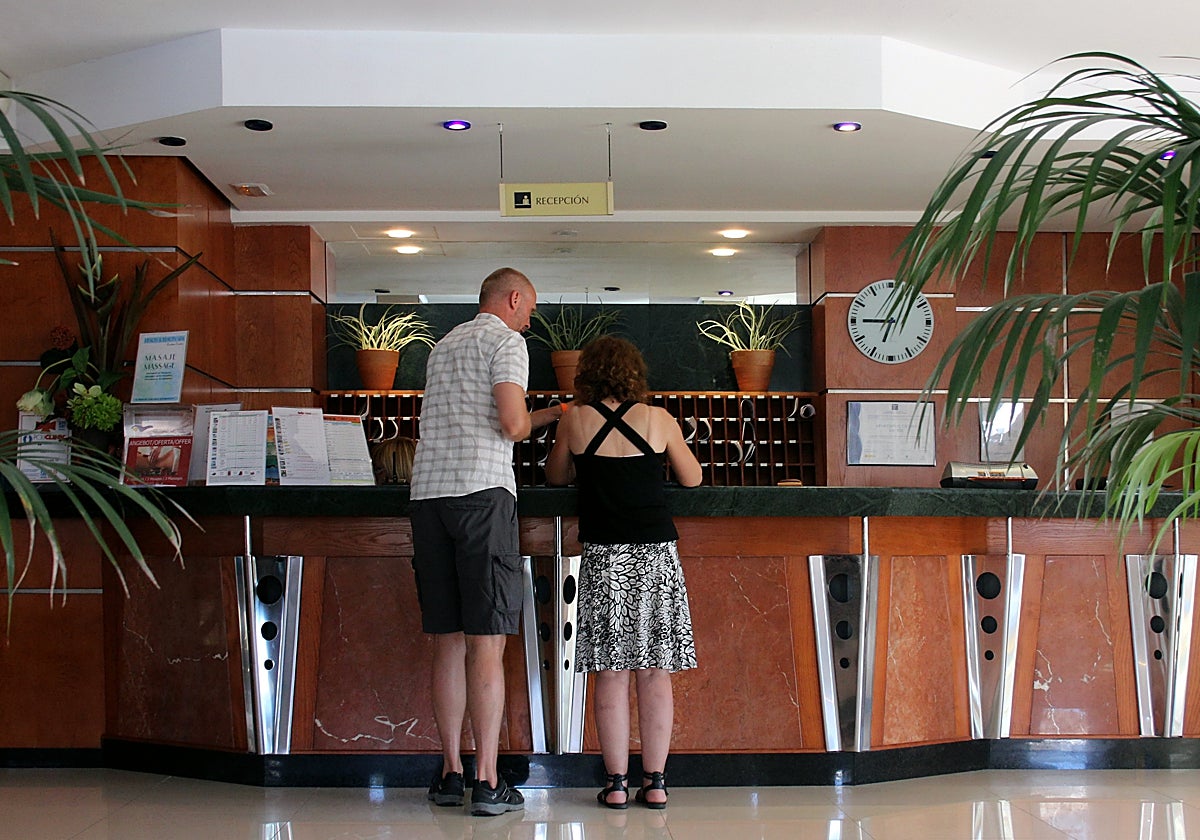Imagen de una pareja de viajeros en la recepción de un hotel