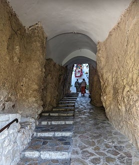 Imagen secundaria 2 - En frente del castillo de San José están los restos del Castillo de la Alcozaiba, también del siglo XI, con un complicado acceso (no se puede visitar) del que sólo queda una torre en ruinas. Sobre estas líneas, el túnel que da acceso a la zona con más historia de Guadalest, y la plaza en agosto, en días de fiesta