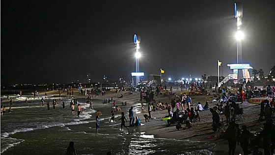Playas nocturnas con reflectores y socorristas con binoculares de visión nocturna