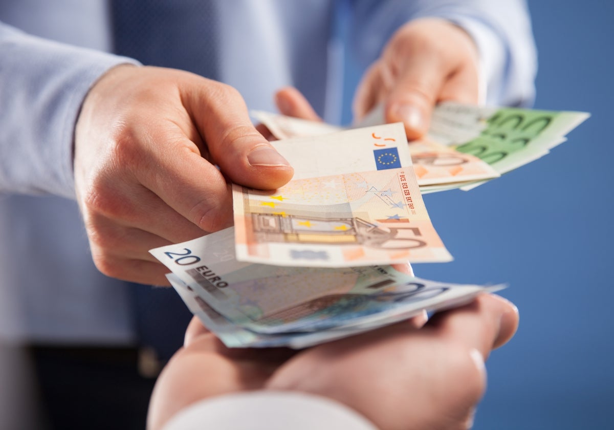 Imagen de una persona entregando varios billetes de euro a otra
