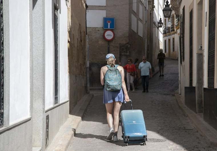 Una chica arrastra una maleta por el casco histórico de una ciudad andaluza