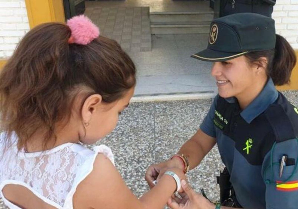 Una agente de la Guardia Civil colocándole a una menor de edad la pulsera