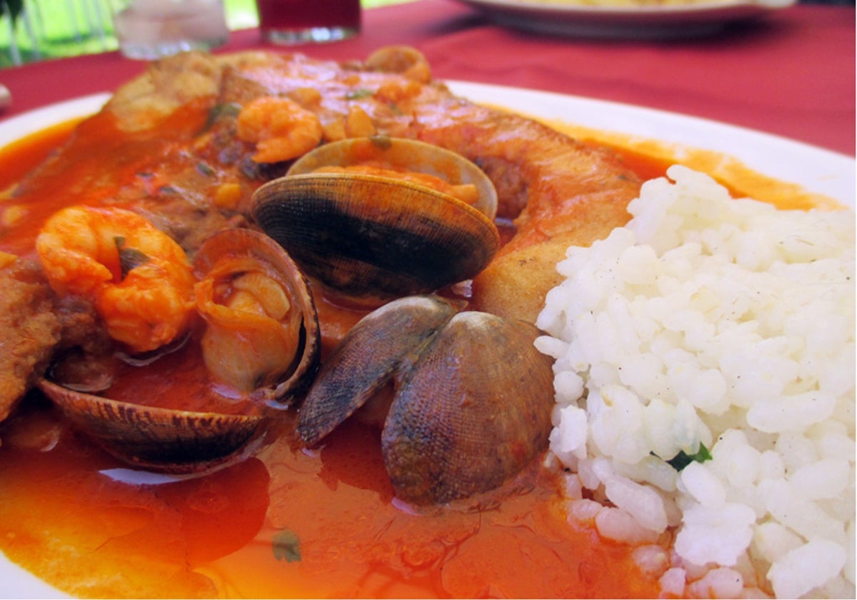 Plato de merluza en salsa con almejas y arroz servido en el restaurante Las Dunas del Portil