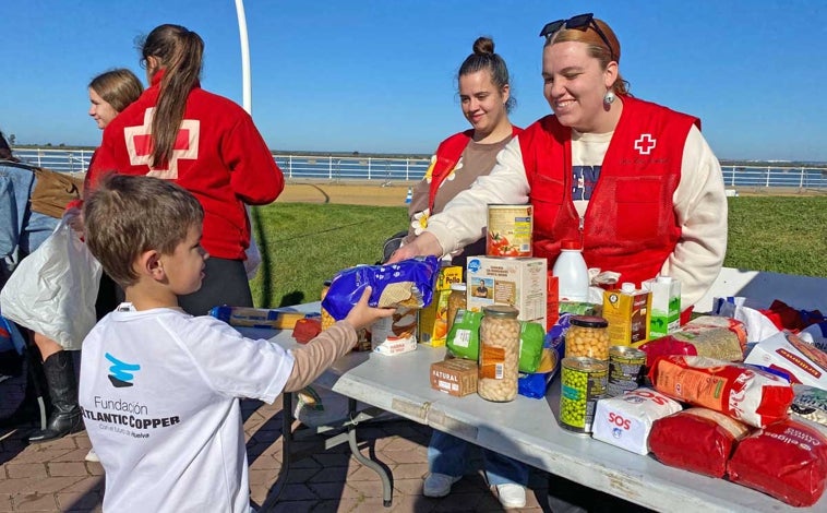 Imagen principal - Arriba, un niño entrega alimentos al personal de Cruz Roja, entidad colaboradora. Sobre estas líneas, el director de la Fundación Atlantic Copper, Antonio de la Vega, entre Teresa Herrera y Patricia Mauri