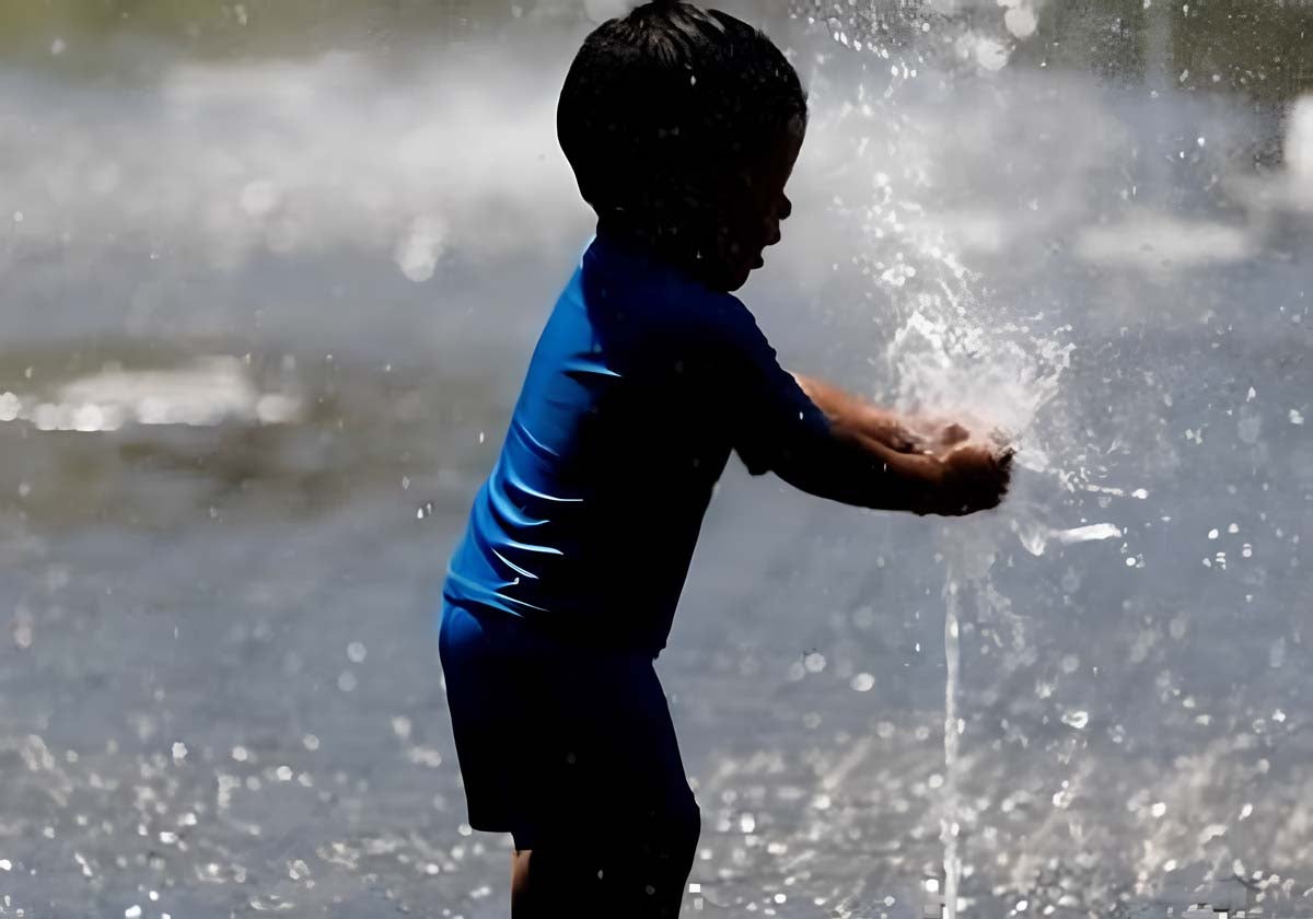 Un niño se refresca en una fuente
