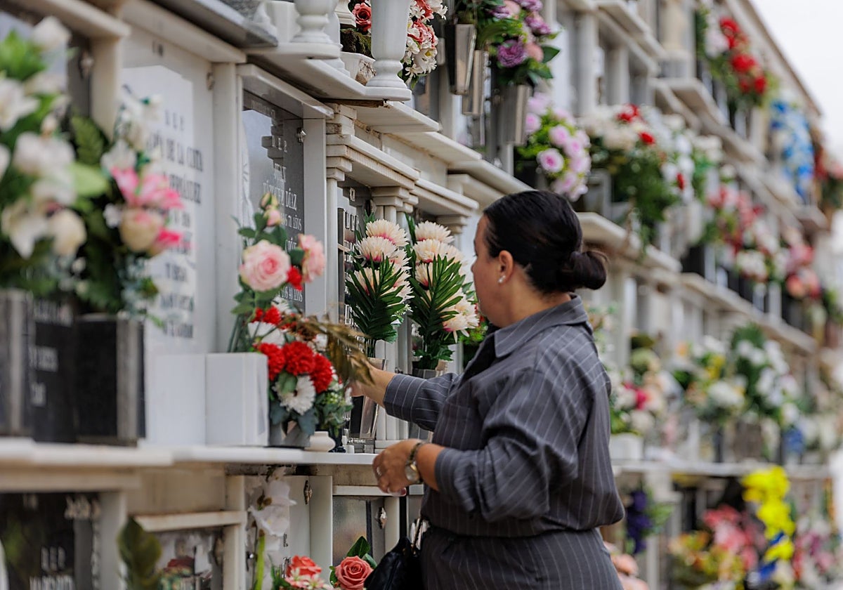 Una mujer coloca flores en un nicho