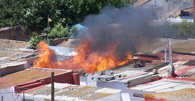 Los bomberos trabajan en la extinción de un incendio en un solar de la barriada de Santa Lucía
