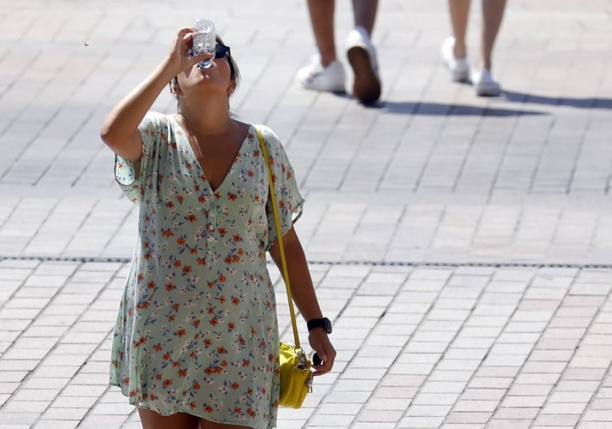 Una chica bebe agua bajo el sol