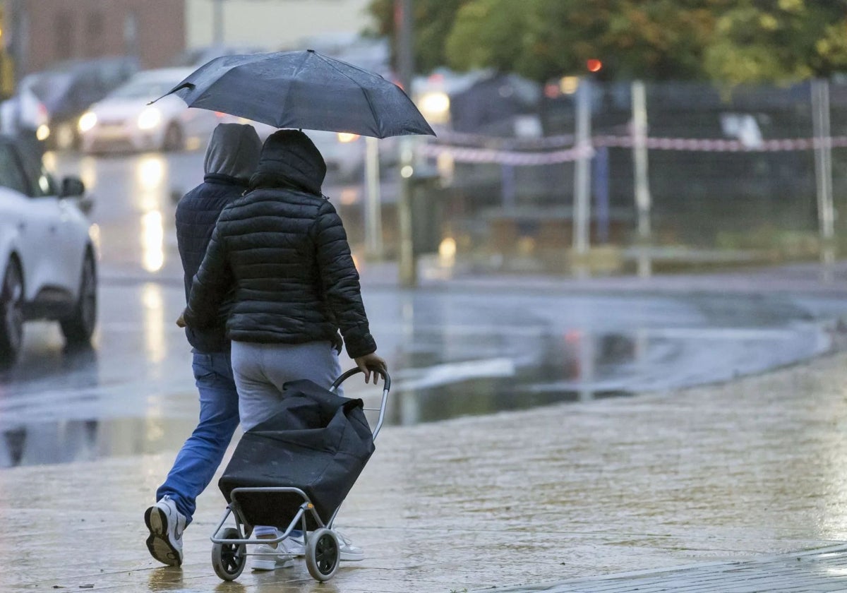 Dos onubenses se protegen de la lluvia con un paraguas en Huelva